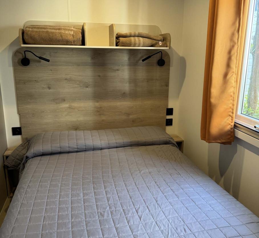Cozy room with a neat bed, soft lights, and warm curtains.