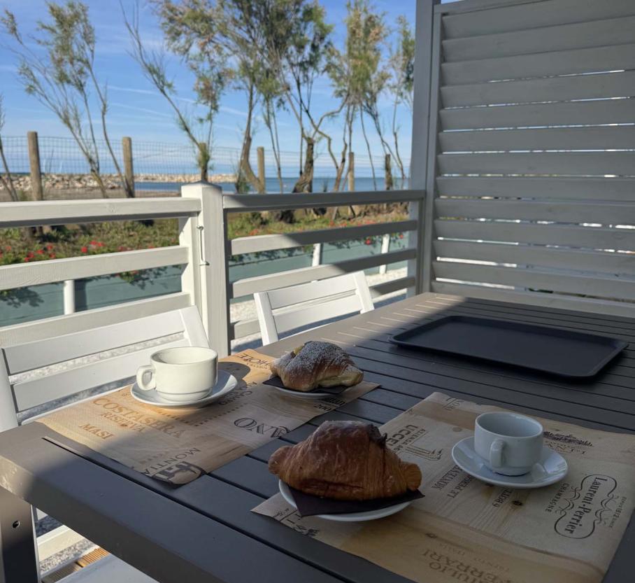 Seaside breakfast: croissants, coffee, and sunshine through the trees.