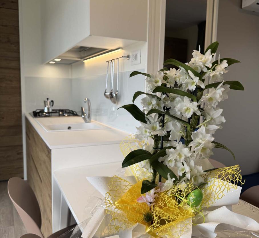 Modern kitchen with white flowers and yellow decorations, cozy atmosphere.