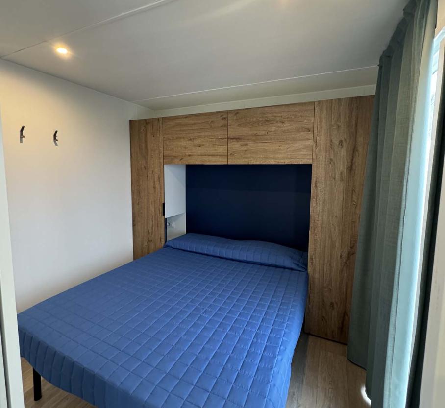 Cozy room with a blue double bed and warm lighting.